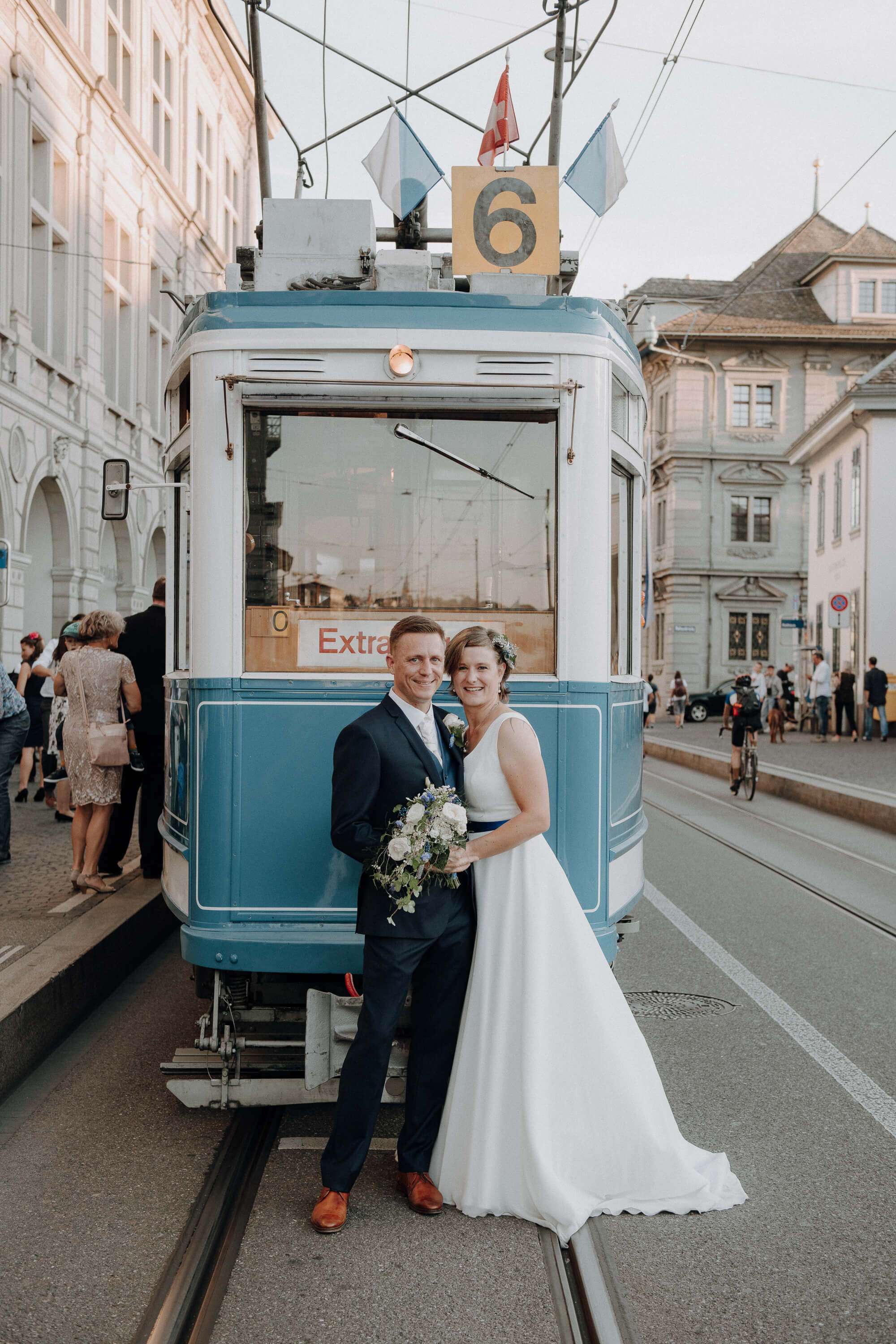 Brautpaar vor einem historischen blauen Zürcher Tram der Linie 6, der Bräutigam im dunkelblauen Anzug